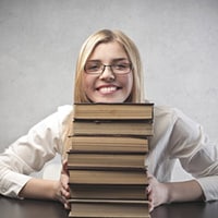 Woman with pile of books learning how to publish your book